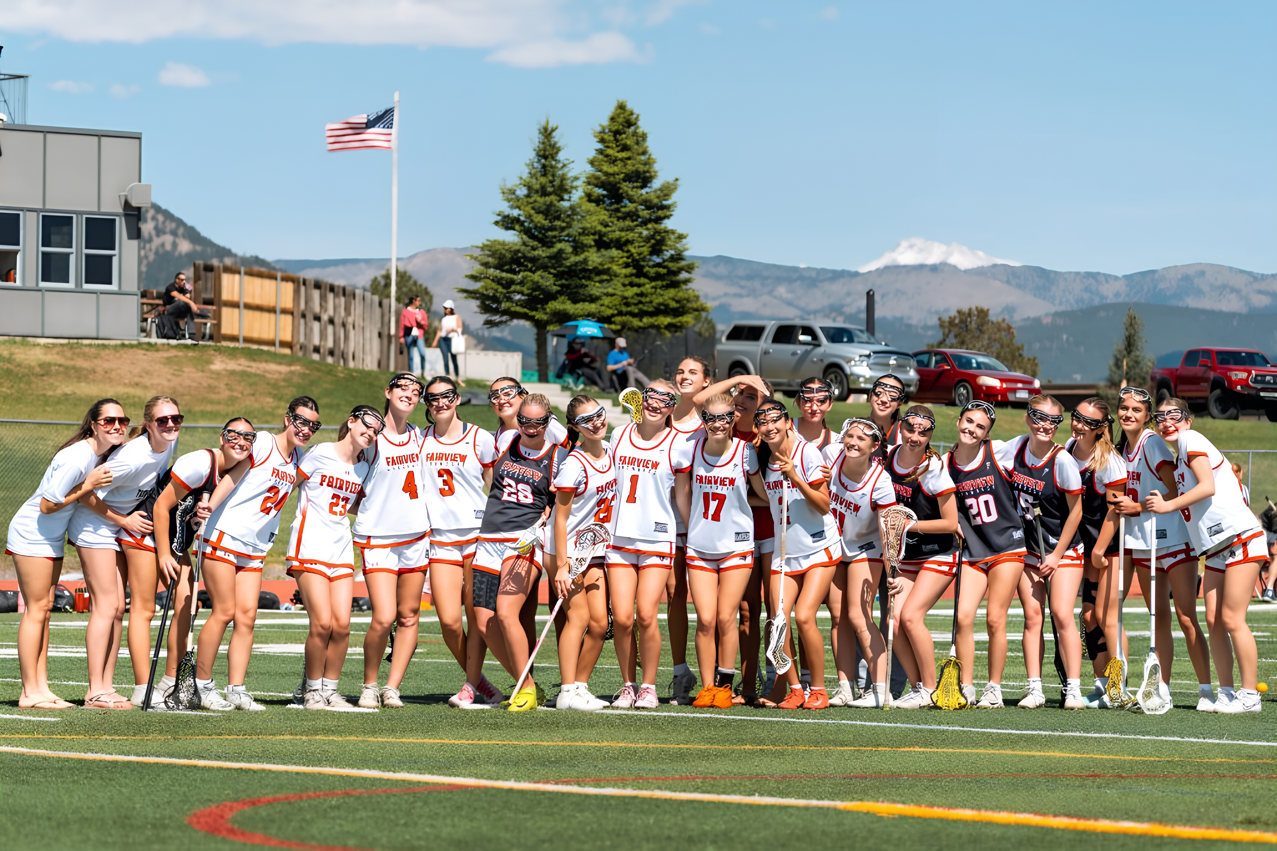 Fairview Knights girls lacrosse team posing together on the field, with the Boulder foothills and an American flag in the background