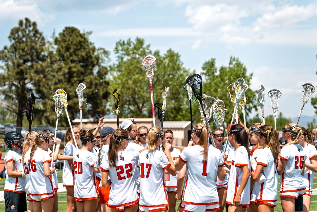Fairview Knights lacrosse team huddled together with sticks raised