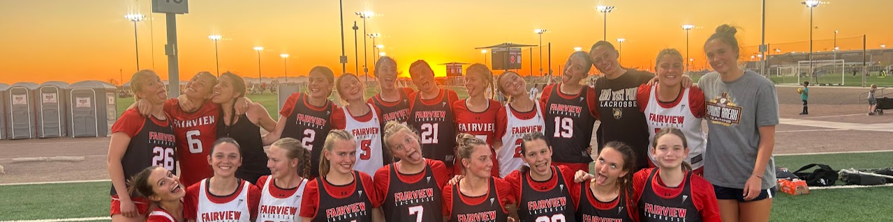 Fairview Knights girls lacrosse team huddled together on the field at sunset